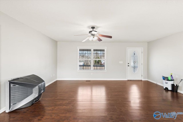 living area featuring baseboards, dark wood finished floors, and a ceiling fan