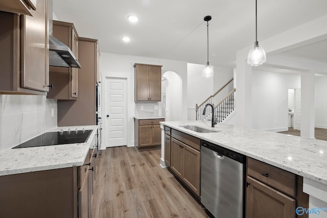 kitchen featuring sink, tasteful backsplash, decorative light fixtures, dishwasher, and light hardwood / wood-style floors