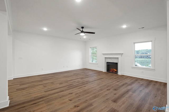 unfurnished living room featuring dark wood-type flooring, plenty of natural light, a high end fireplace, and ornamental molding