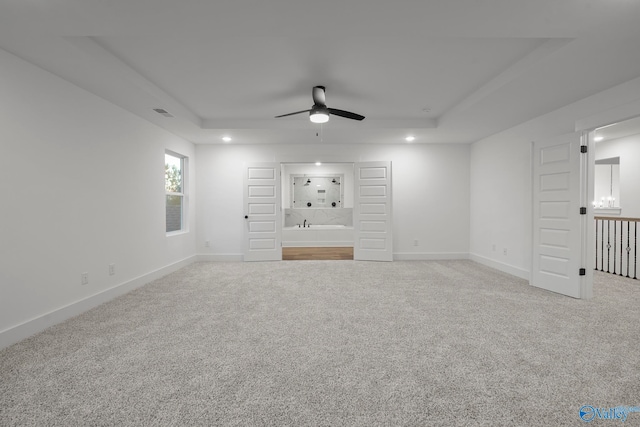 unfurnished living room featuring carpet floors, a raised ceiling, and ceiling fan