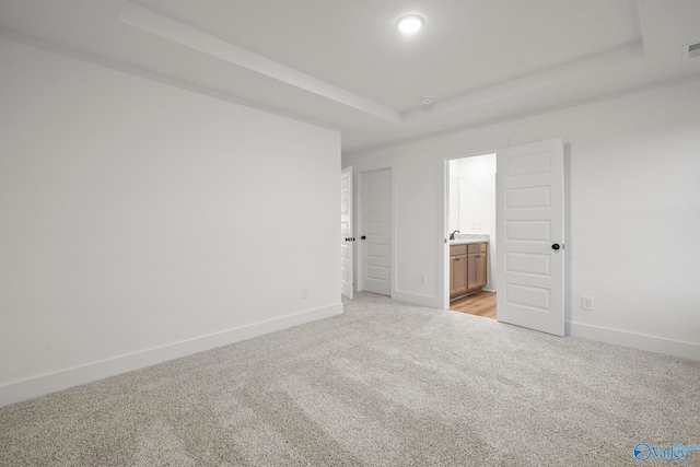 empty room with a raised ceiling and light carpet