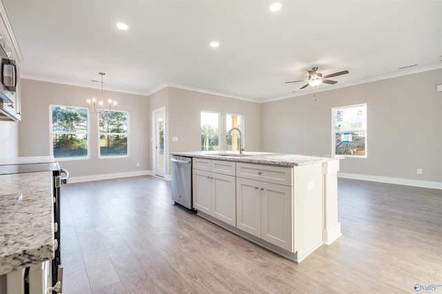 kitchen with pendant lighting, an island with sink, sink, stainless steel appliances, and light stone countertops