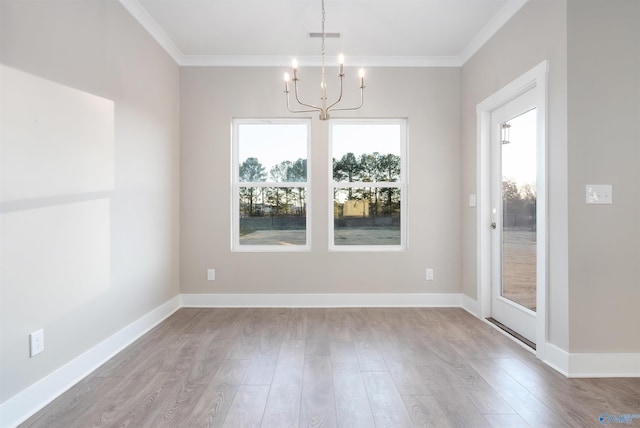 unfurnished dining area featuring an inviting chandelier, ornamental molding, and light hardwood / wood-style floors