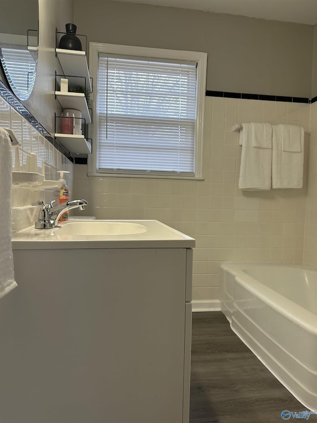 bathroom with vanity, hardwood / wood-style floors, tile walls, and a bathtub