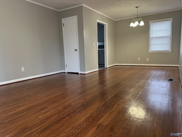 spare room featuring a notable chandelier, dark wood-type flooring, and ornamental molding