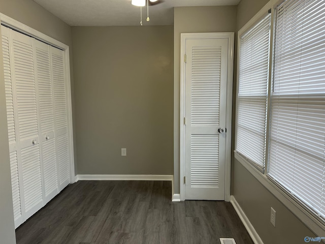 unfurnished bedroom with dark wood-type flooring and a closet