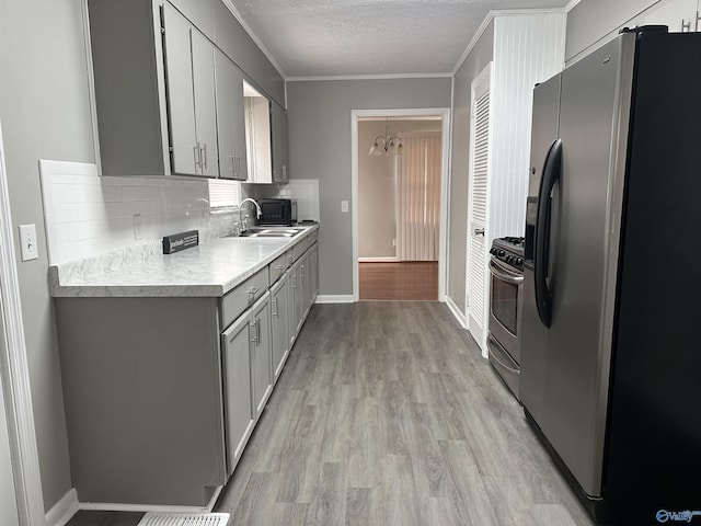 kitchen featuring appliances with stainless steel finishes, sink, gray cabinetry, and light hardwood / wood-style flooring