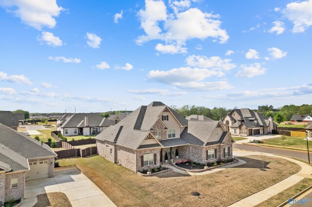 view of front of home featuring concrete driveway, a residential view, stone siding, and fence