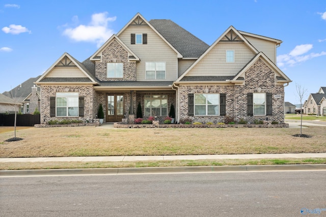 craftsman house with brick siding, a front lawn, and a shingled roof