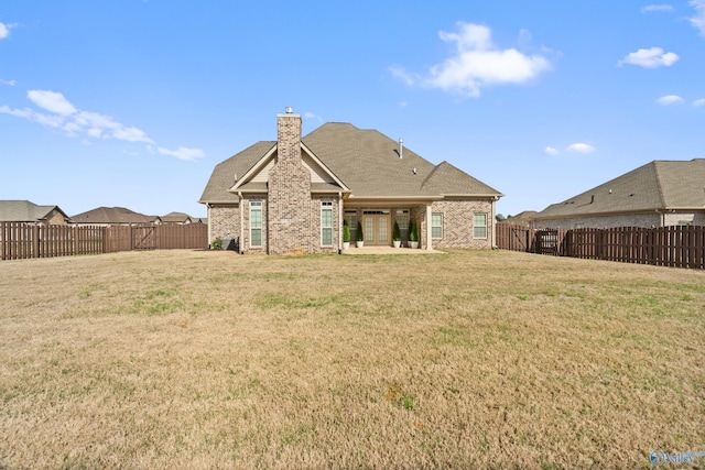 rear view of house featuring a yard, a fenced backyard, a chimney, and a patio area