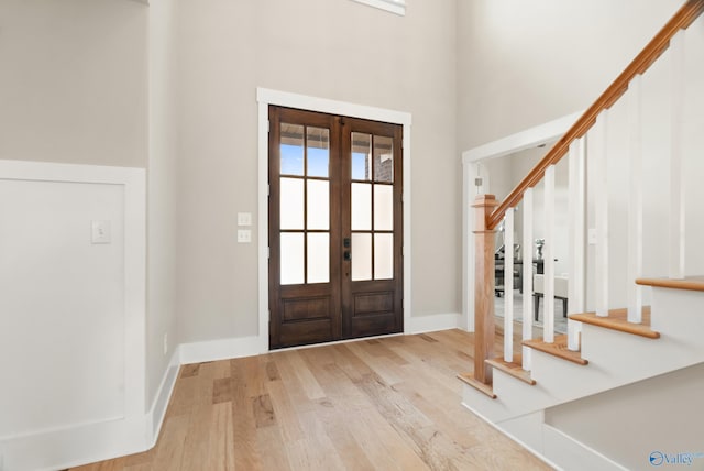 foyer entrance featuring stairway, wood finished floors, a high ceiling, french doors, and baseboards