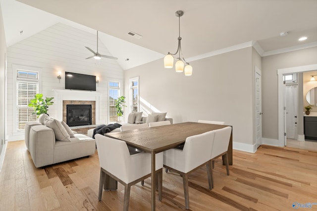 dining area featuring a glass covered fireplace, baseboards, a ceiling fan, light wood-style floors, and visible vents