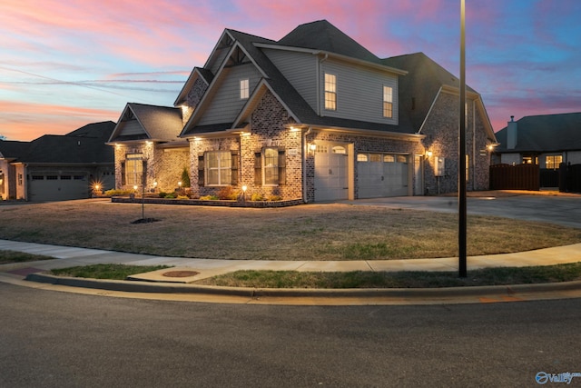 view of front of property featuring concrete driveway, a front lawn, brick siding, a garage, and fence