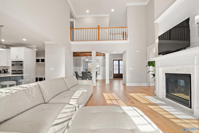 living room with baseboards, a fireplace, light wood-type flooring, and crown molding