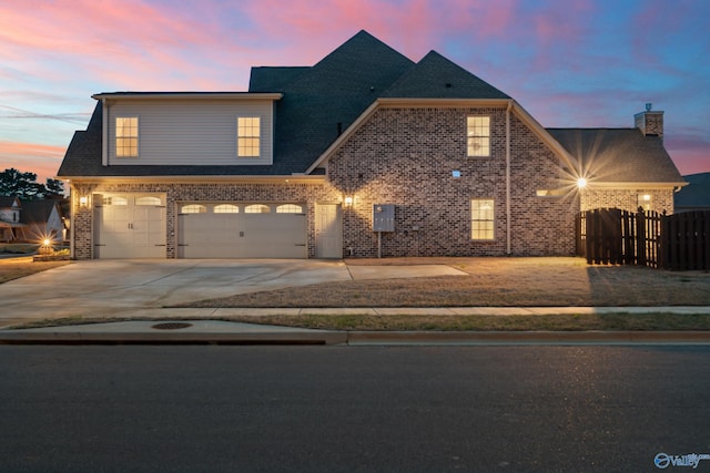 view of front of house with a garage, brick siding, driveway, and fence