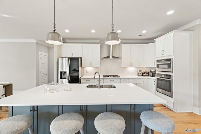 kitchen featuring light wood-style flooring, backsplash, wall chimney exhaust hood, stainless steel appliances, and a sink