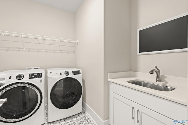 laundry area featuring a sink, washing machine and clothes dryer, cabinet space, and baseboards