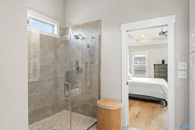 ensuite bathroom featuring a raised ceiling, connected bathroom, a stall shower, and wood finished floors