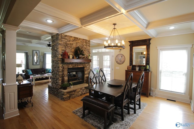 dining area featuring ceiling fan with notable chandelier, light hardwood / wood-style floors, a healthy amount of sunlight, and a fireplace