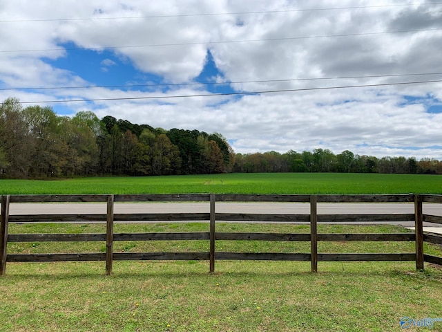 view of gate with a yard, a rural view, and fence