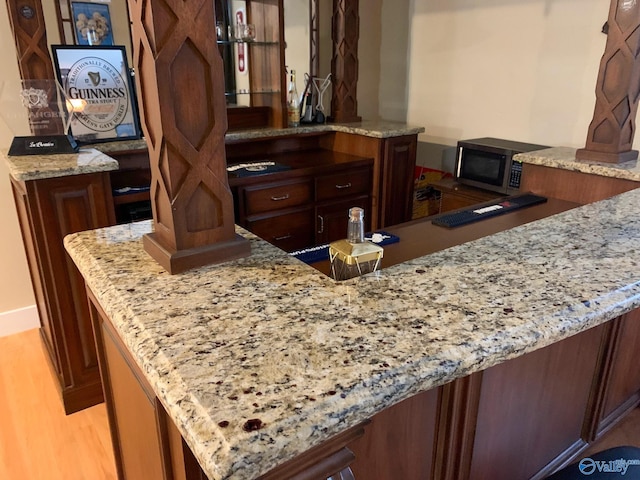 kitchen featuring light hardwood / wood-style floors, light stone countertops, and kitchen peninsula