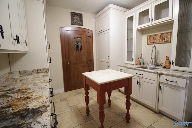 kitchen with white cabinets, light stone counters, sink, and light tile patterned floors