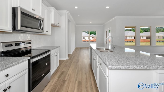 kitchen featuring a center island with sink, sink, white cabinetry, and stainless steel appliances