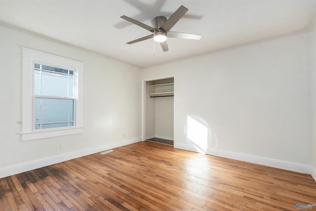 unfurnished bedroom featuring hardwood / wood-style floors, ceiling fan, crown molding, and a closet