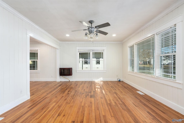 unfurnished living room featuring hardwood / wood-style flooring, ceiling fan, crown molding, and heating unit