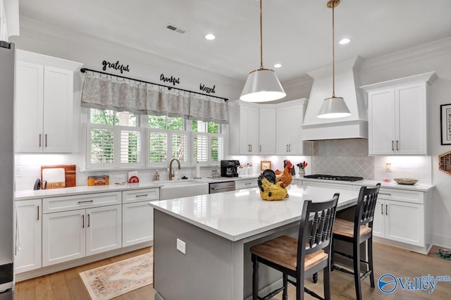 kitchen with visible vents, a sink, light countertops, ornamental molding, and white cabinetry