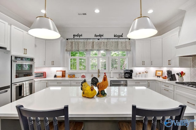 kitchen featuring light countertops, stainless steel appliances, recessed lighting, a kitchen bar, and custom exhaust hood