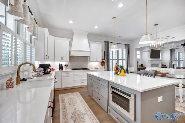 kitchen with ornamental molding, a center island, custom range hood, a sink, and backsplash