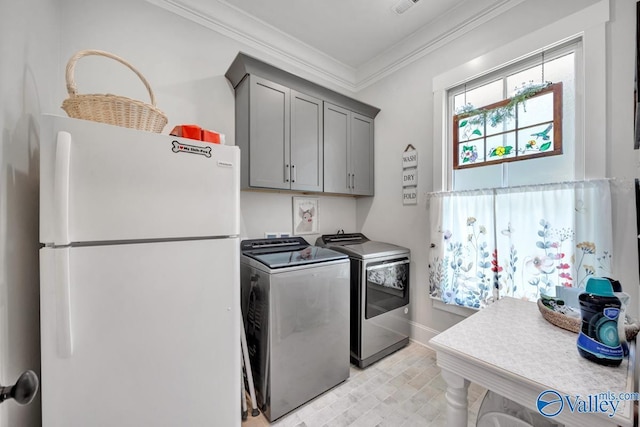 laundry area featuring crown molding, baseboards, cabinet space, and washer and dryer
