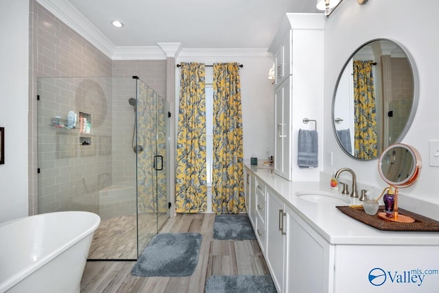bathroom with crown molding, a freestanding bath, vanity, a shower stall, and wood finished floors