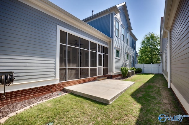 exterior space with a lawn, a patio, fence, and a sunroom