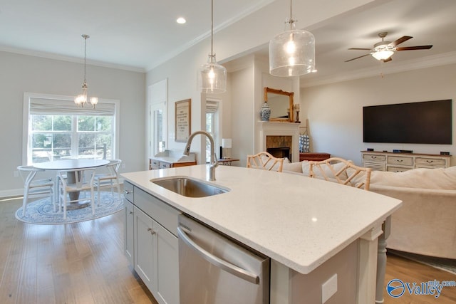 kitchen with open floor plan, wood finished floors, stainless steel dishwasher, a fireplace, and a sink