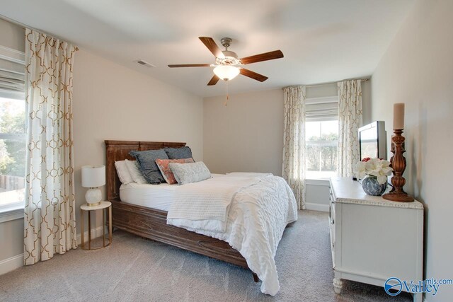 bedroom with light carpet, ceiling fan, visible vents, and baseboards