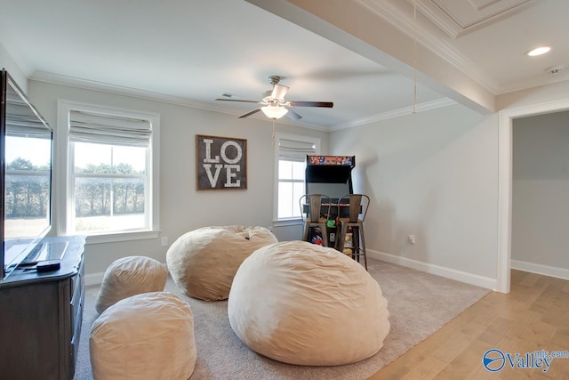 living area with attic access, baseboards, ceiling fan, light wood-style flooring, and crown molding