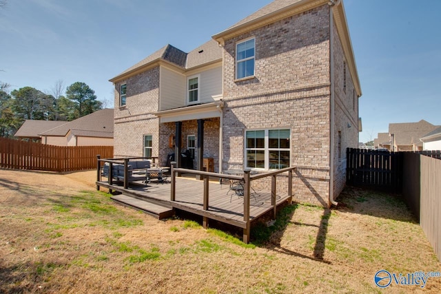 back of property with a yard, brick siding, and a fenced backyard