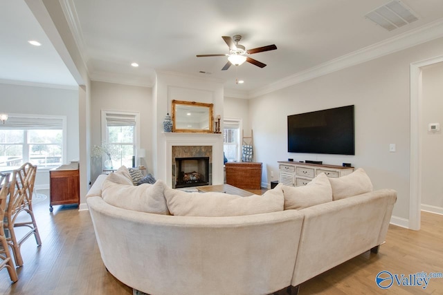 living area with light wood-style flooring, visible vents, and crown molding