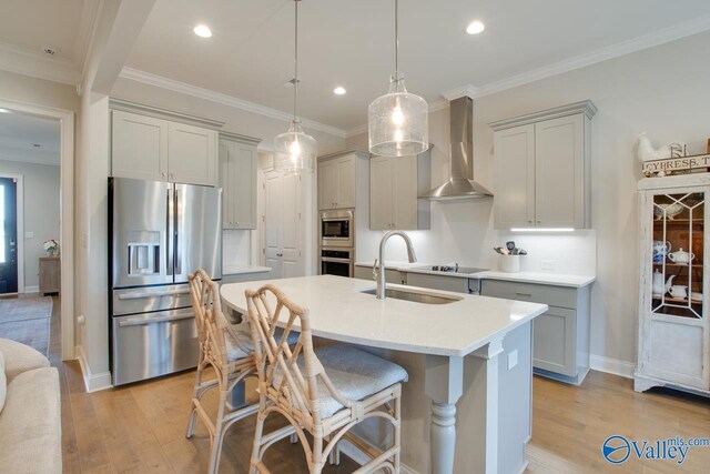 kitchen featuring stainless steel appliances, wall chimney range hood, gray cabinets, and a sink