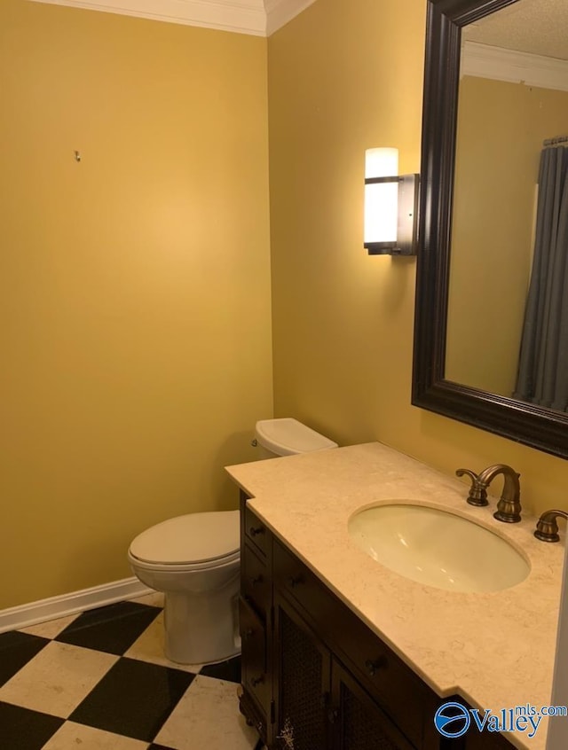 bathroom featuring toilet, vanity, baseboards, tile patterned floors, and crown molding