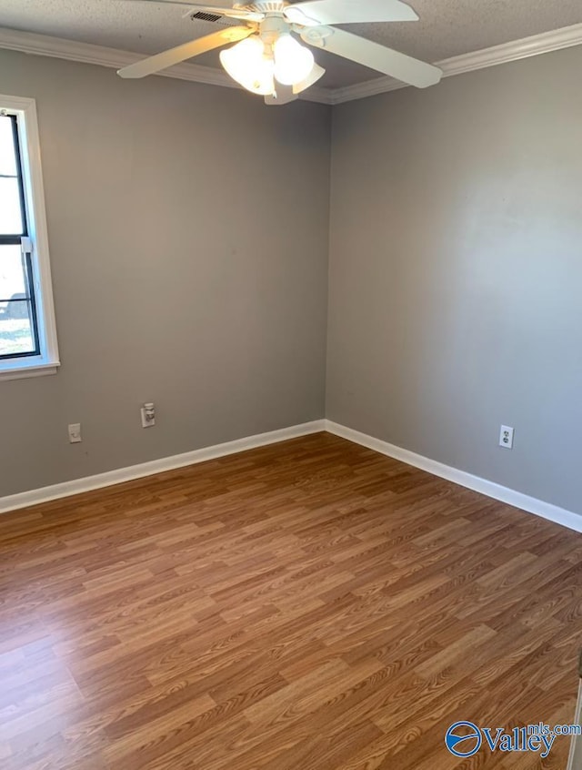 spare room with baseboards, a textured ceiling, ornamental molding, and wood finished floors