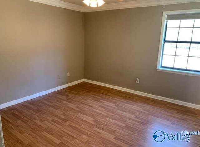 spare room featuring baseboards, ornamental molding, and wood finished floors