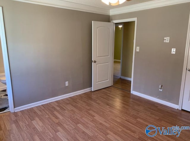 unfurnished room with ornamental molding, wood finished floors, and baseboards