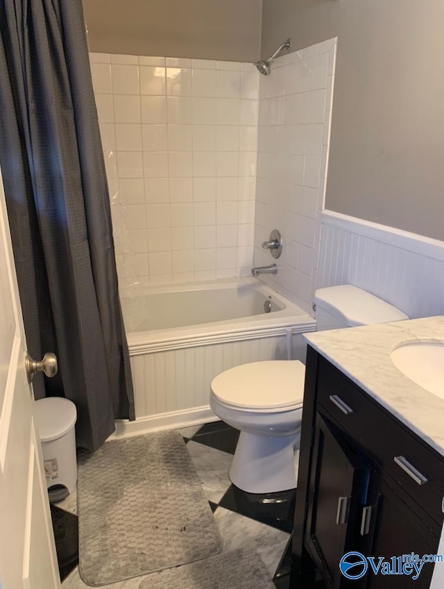 full bath featuring toilet, vanity, shower / bath combination with curtain, and wainscoting