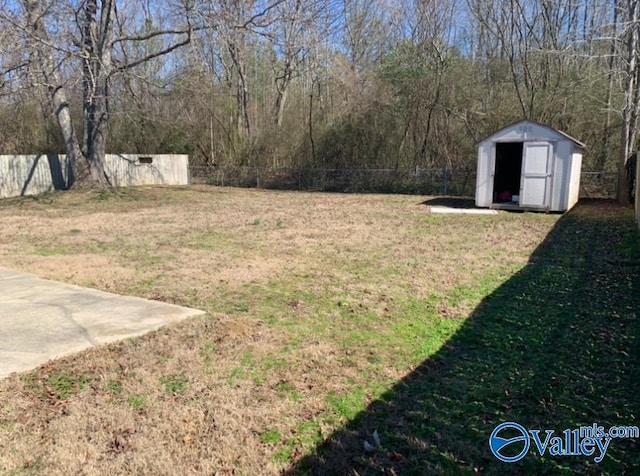 view of yard featuring a patio area, a fenced backyard, a storage unit, and an outbuilding