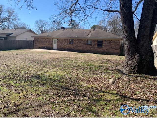 back of property featuring a yard, brick siding, and fence