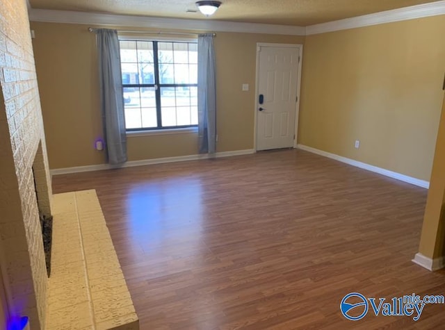 unfurnished living room with baseboards, dark wood-style floors, ornamental molding, a textured ceiling, and a brick fireplace