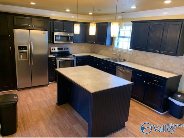 kitchen with stainless steel appliances, light countertops, decorative light fixtures, and a center island